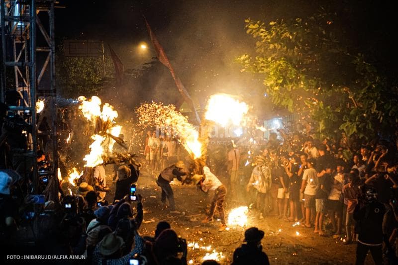 Peperangan obor antardua laki-laki dengan membawa pelepah kelapa yang dibakar