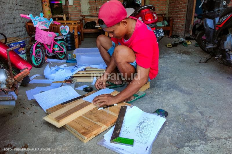 Proses awal pembuatan gebyok, membuat pola di kayu jati sebelum diukir.