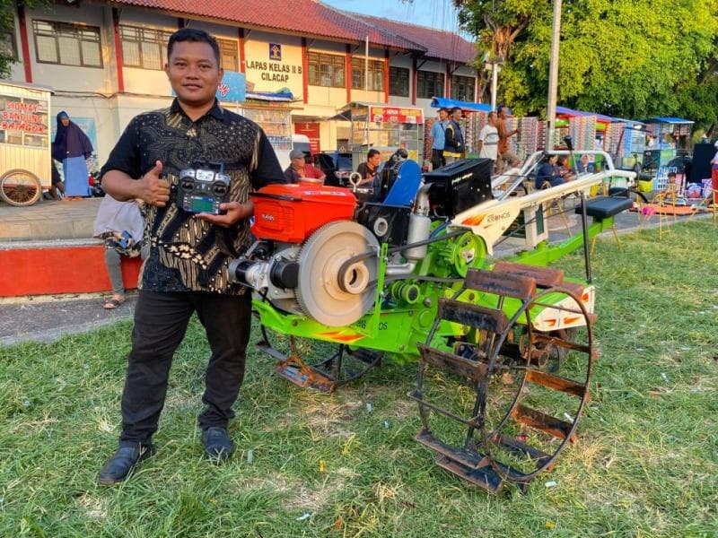 Wahid Hasyim, seorang petani asal Kebumen berpose di samping Traktor Siluman ciptaannya. (Diskominfo Jateng)