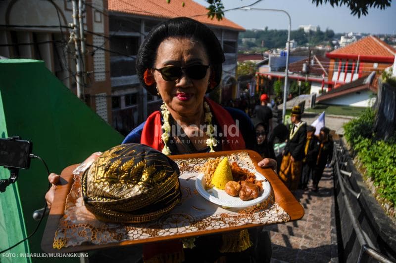 Seorang pengelola Yayasan Ki Ageng Pandanaran membawa blangkon dan ujung tumpeng menuju Makam Ki Ageng Pandanaran sebelum penggantian luwur dilakukan.