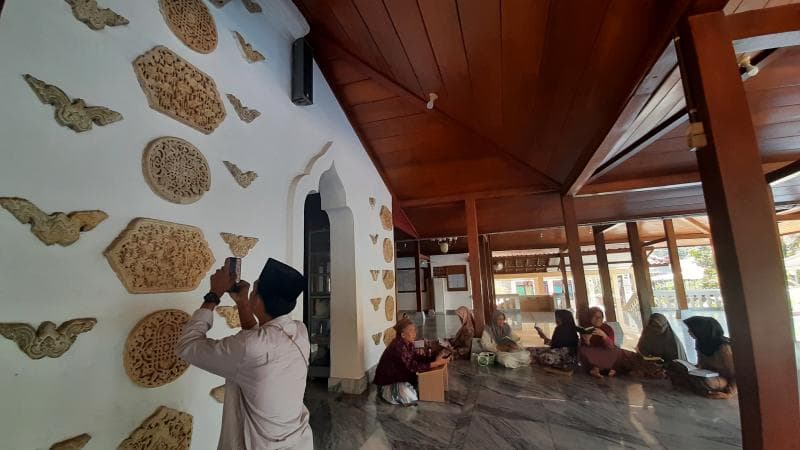 Seorang pengunjung sedang mengabadikan relief yang tertempel di dinding masjid. (Inibaru.id/ Imam Khanafi)