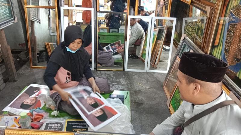 Seorang pedagang tengah memilah dagangan foto pigura Presiden dan Wakil Presiden RI di PKL sebelah Pos Johar, Rabu (23/10). (Inibaru.id/ Danny Adriadhi Utama)