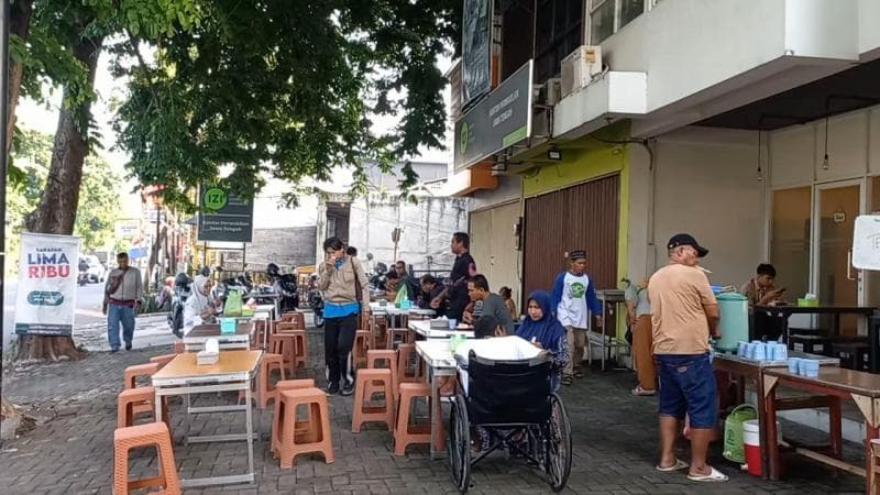 Suasana warga tengah menikmati makan sedekah lima ribu di&nbsp;Jalan Basudewo tepatnya di Banjir Kanal Barat. (Inibaru.id/ Danny Adriadhi Utama)