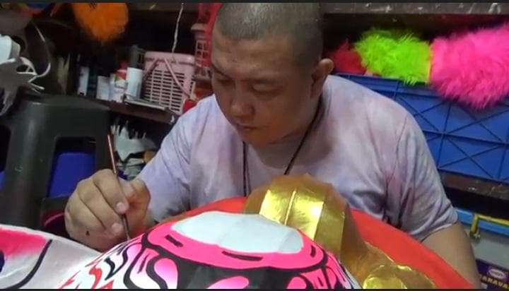 Huang Wie Hong, perajin barongsai asal Semarang tengah memoles hasil karyanya dengan cat agar tampak molek. (Inibaru.id/ Danny Adriadhi Utama)