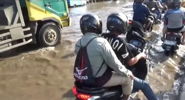 Para pengendara motor menerjang banjir terlihat jalan pelan-pelan menghindari lubang. (Inibaru.id / Danny Adriadhi Utama)