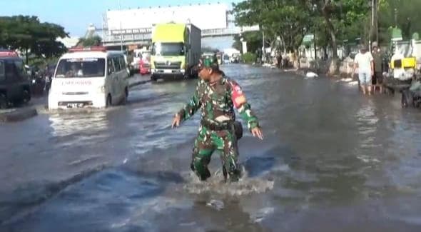 Anggota Babinsa Kelurahan Terboyo Kulon Serda Suliman turut membantu mengurai kemacetan akibat banjir di Jalan Kaligawe Raya Semarang pada Jumat, 7 Februari 2025. (Inibaru.id/ Danny Adriadhi Utama)