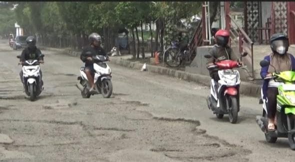 Sejumlah pengendara motor tampak berhati-hati melintas Jalan Kaligawe Kota Semarang lantaran rusak parah dan penuh lubang akibat terdampak hujan dan banjir. (Inibaru.id/Danny Adriadhi Utama).