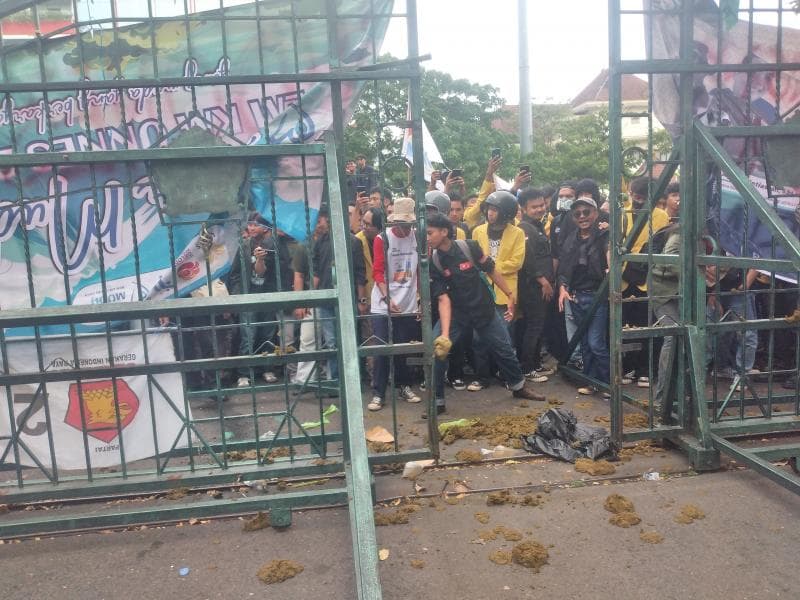 Aksi mahasiswa kritisi efisiensi anggaran dengan membuang tletong (kotoran) sapi di depan pintu gerbang DPRD Jateng. (Inibaru.id/ Danny Adriadhi Utama)