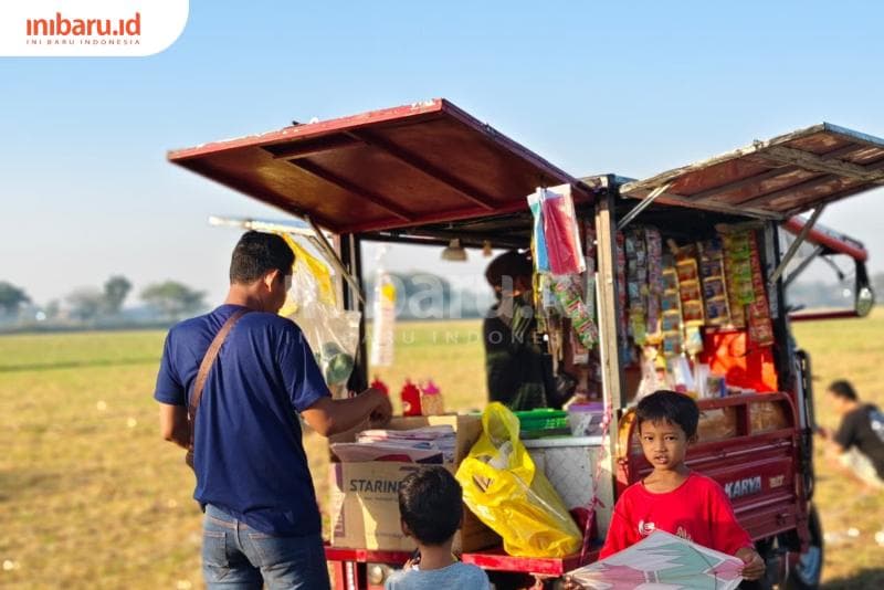 Seorang ayah dan anaknya sedang membeli layang-layang. (Inibaru.id/ Alfia Ainun Nikmah)