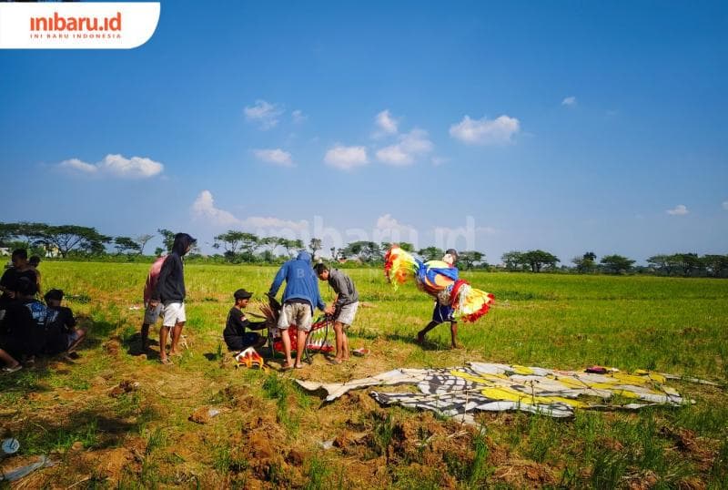 Salah satu kelompok sibuk mempersiapkan kepingan dan kepala naga sebelum diterbangkan (Inibaru.Id/Alfia Ainun Nikmah)