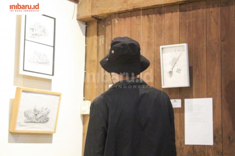 Seorang pengunjung sedang menikmati karya Putut di ruang pamer. (Inibaru.id/Imam Khanafi)