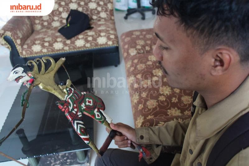 Seorang jurnalis sedang memegang wayang klitik yang membuatnya kagum. (Inibaru.id/Imam Khanafi)