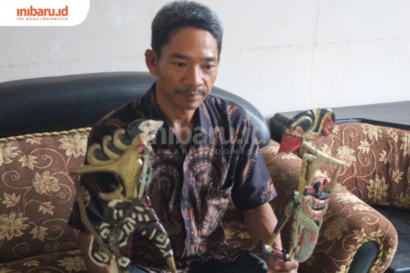Kepala desa Setiyo Budi saat ditemui di balai desa sedang menunjukan wayang klitik. (Inibaru.id/Imam Khanafi)