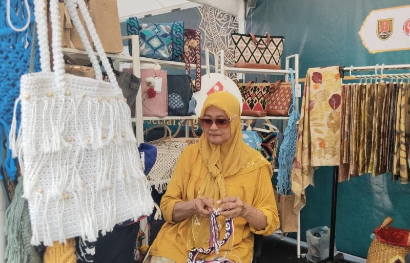 Pemilik Ekkyta Collection, Indah Prihatiningsih saat sedang merajut tali tas saat sedang mengikut kegiatan UMKM di halaman Balai Kota Semarang. (Inibaru.id/Sundara) 