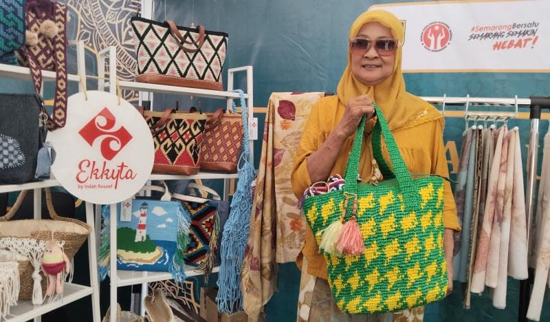 Indah Prihatiningsih saat memperlihatkan tas rajutan yang semua bahannya berasal dari plastik sekali pakai. (Inibaru.id/ Sundara)&nbsp;