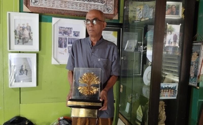 Sururi saat memegang piala penghargaan Kalpataru yang diberikan Menteri Lingkungan Hidup RI kategori perintis lingkungan. (Inibaru.id/ Sundara)&nbsp;