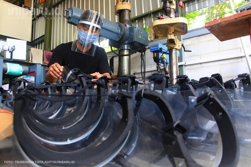 Pekerja memeriksa face shield yang sudah siap pakai.