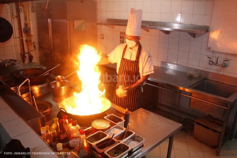 Koki di dapur PO Hotel Semarang menggunakan masker dan sarung tangan saat memasak agar makanan tetap steril dari virus.