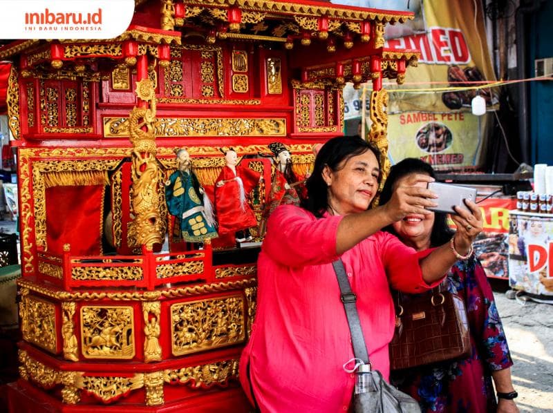 Pengunjung Pasar Imlek Semawis berswafoto di depan panggung kecil Wayang Potehi. (Inibaru.id/ Audrian F)<br>