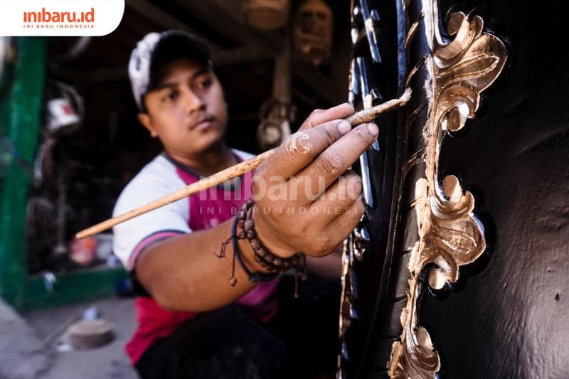 Farid Fatullah, anak Mustofa sedang mengecat kaligrafi beduk. (Inibaru.id/ Audrian F)<br>