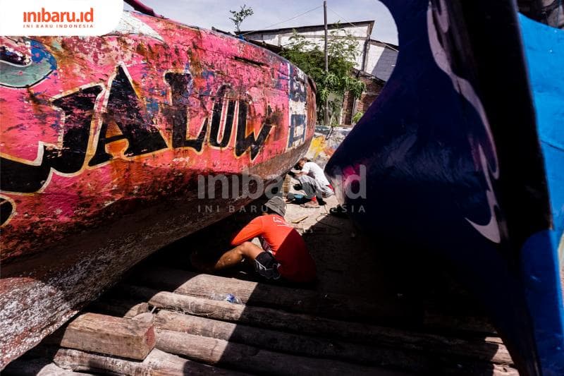 Menambal lubang-lubang di bawah kapal. (Inibaru.id/ Audrian F)<br>