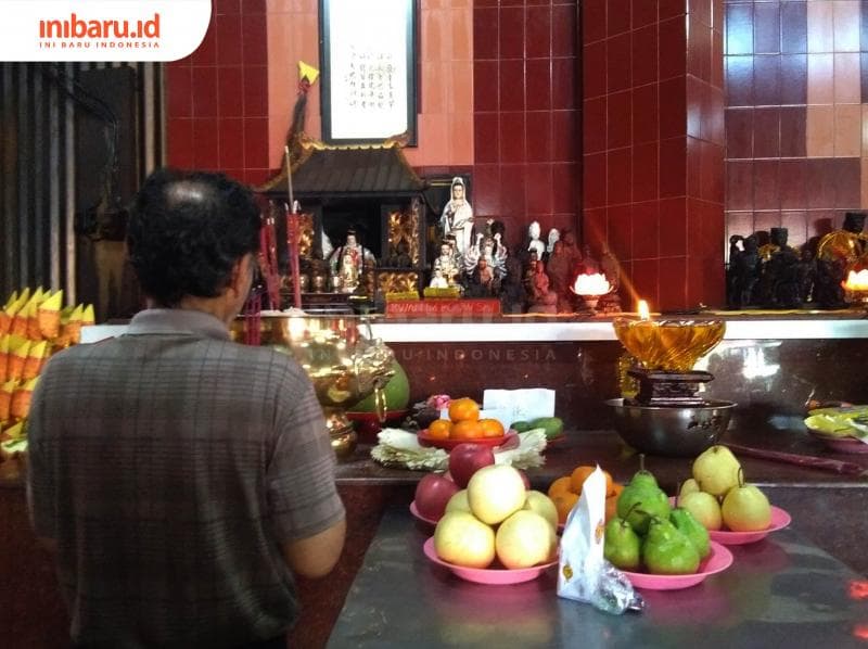 Seorang umat Tridharma berdoa di depan rupang dewa. (Inibaru.id/ Isma Swastiningrum)<br>