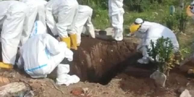Proses pemakaman oleh petugas medis menggunakan tangan. (Kompas)<br>