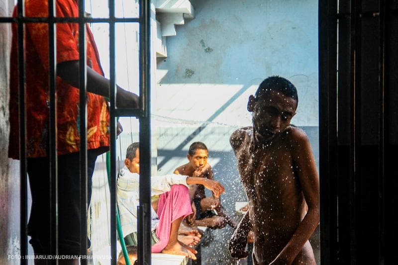 Petugas memandikan warga binaan Among Jiwo dengan disiram air.<br>