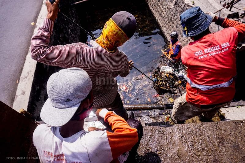 Bahu-membahu mengangkut sampah penyumbat selokan.<br>