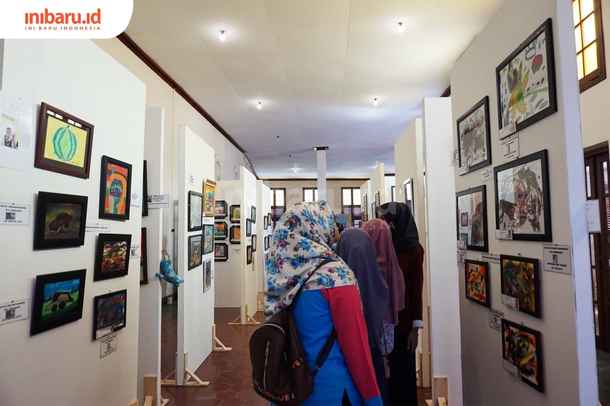 Pengunjung sedang mengamati lukisan dalam Pameran Lukisan Anak Hebat, Selasa (2/4/2019) di Gedung Monod Diephuis & Co. (Inibaru.id/ Ida Fitriyah)