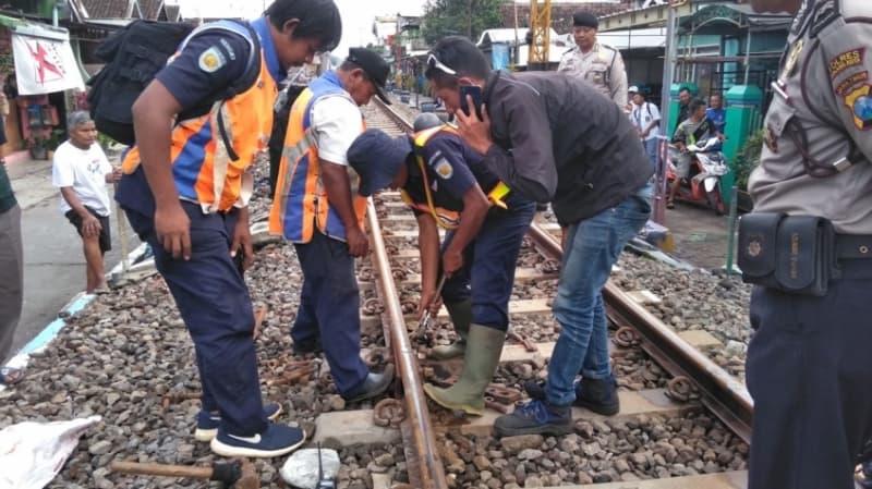 Petugas PT KAI memperbaiki rel yang merenggang. (surabayapost.net)