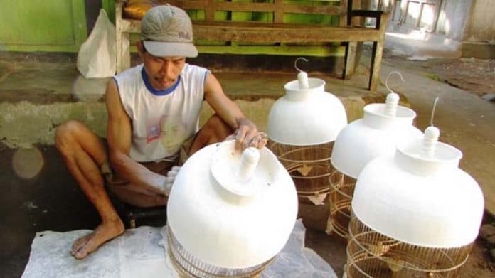 Salah seorang pengrajin sangkar burung di Desa Wirun sedang mengecat produknya. (koranpurworejo.id) .