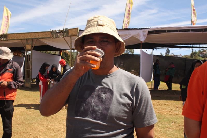 Salah seorang relawan aksi "Dieng Bersih" menikmati segelas minuman purwaceng. (Putri Rachmawati/Inibaru.id)