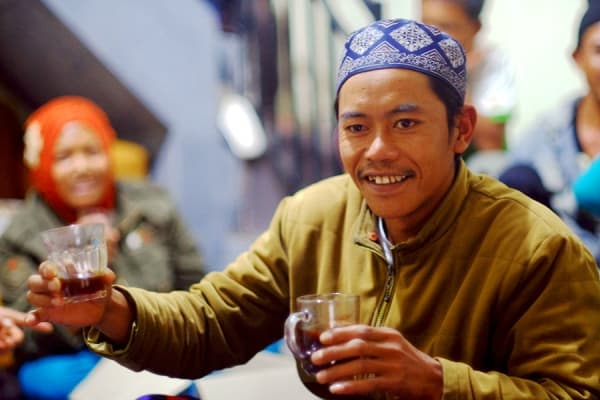 Seorang petani kopi arabika Ratamba dengan segelas kopi seduh arabika Ratamba. (Klinikkopi)