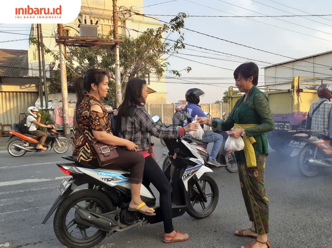 Peserta dengan pakaian tradisional sedang membagikan takjil pada pengguna jalan. (Inibaru.id/ Zulfa Anisah)