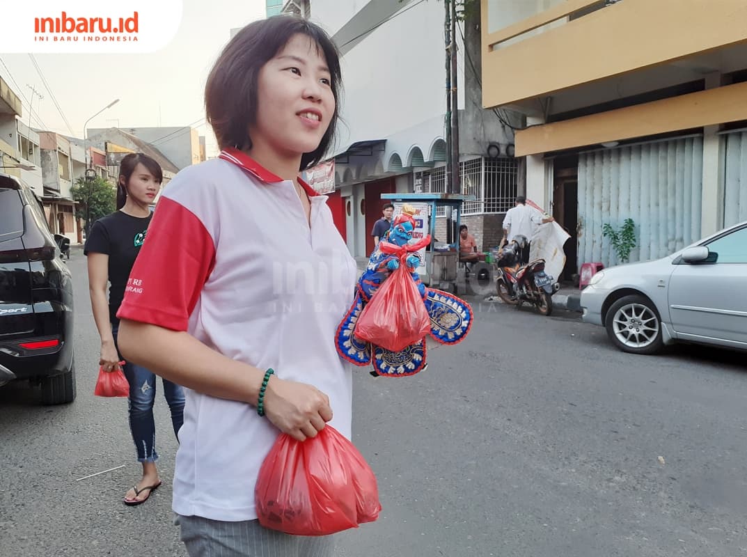 Seorang jemaat klenteng sedang menghadang pengguna jalan untuk memberikan takjil. (Inibaru.id/ Zulfa Anisah)