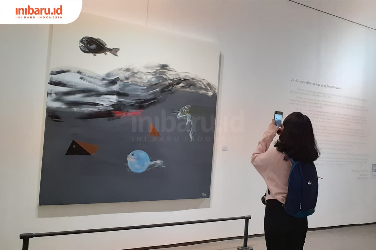 Seorang pengunjung sedang memotret lukisan Goenawan Mohamad berjudul Ikan dan Lainnya. (Inibaru.id/ Zulfa Anisah)