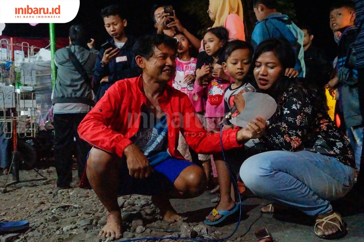 Sigit Susanto (merah), turun langsung untuk mengajak pengunjung untuk membaca puisi. (Inibaru.id/ Audrian F)