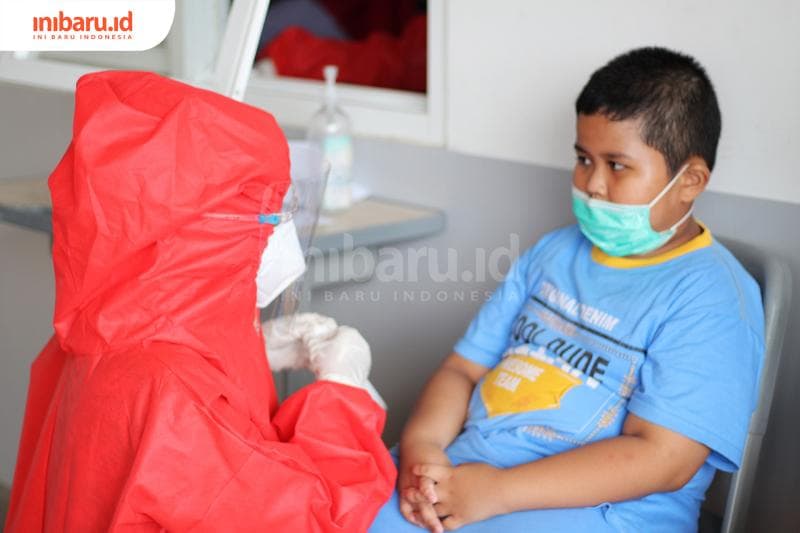 Seorang anak bersiap melakukan Rapid Test Antigen di area Bandara Internasional Jenderal Ahmad Yani Semarang, Jawa Tengah, Senin (28/12/2020). Mereka yang hendak berlibur ke luar kota wajib menunjukkan hasil negatif rapid test antigen.<br>