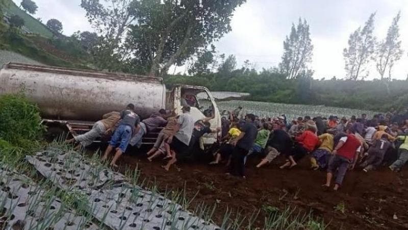 Warga Karanganyar mengevakuasi truk yang terperosok di lahan pertanian. (Fajar.co.id)