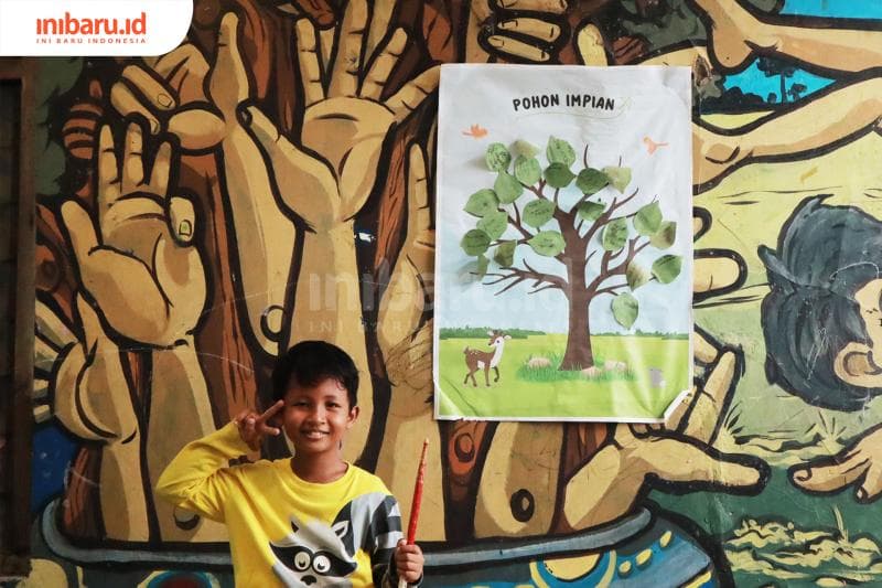 Salah seorang siswa di Rubbik School dengan 'Pohon Impian' di sampingnya.&nbsp;(Inibaru.id/ Bayu N)