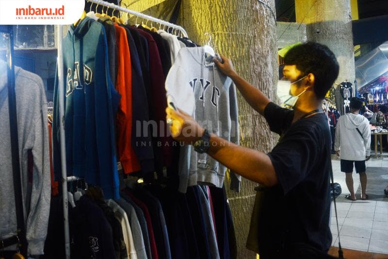 Salah seorang pembeli sedang melihat barang-barang thrift yang dipajang di bazar clothing di Kota Semarang, belum lama ini.&nbsp;(Inibaru.id/ Kharisma Ghana Tawakal)