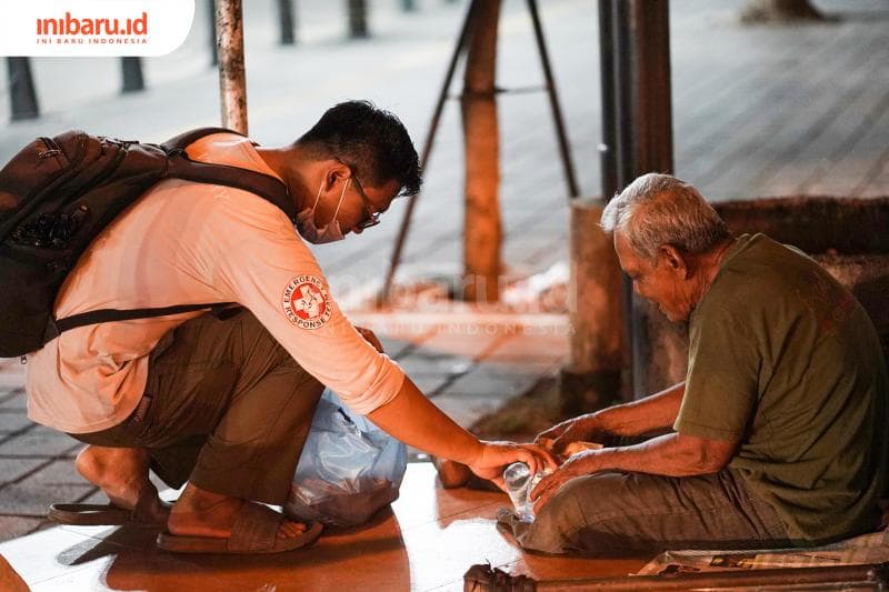 Wijaya memberikan makanan dan minuman kepada seorang tunawisma yang sudah tinggal bertahun-tahun di dekat Jembatan Mberok. (Inibaru.id/ Bayu N)