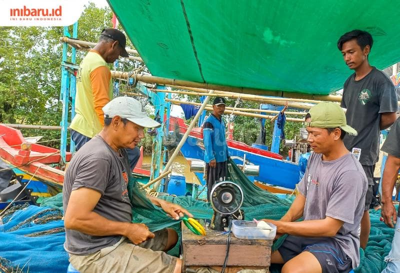 Dua orang nelayan Sendang Sikucing sedang menjahit jaring berukuran 400 meter. (Inibaru.id/Fitroh Nurikhsan)