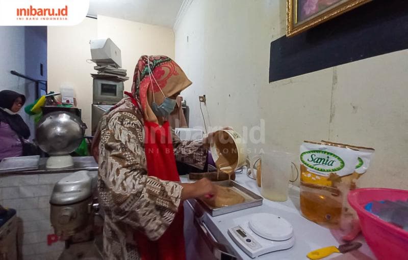 Pemilik Omah Ganjel Rel Aunil Fadlilah tengah menuang adonan roti ganjel rel ke loyang.&nbsp;(Inibaru.id/ Fitroh Nurikhsan)