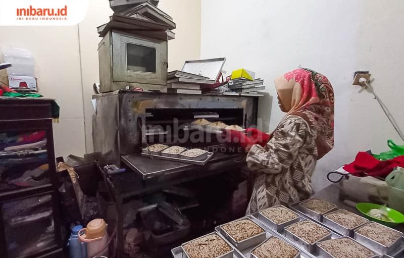 Aunil Fadlilah sedang mengangkat roti ganjel rel yang telah dimasukkan ke dalam oven.&nbsp;(Inibaru.id/ Fitroh Nurikhsan)