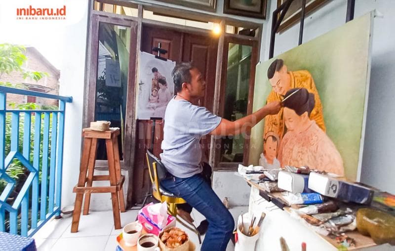 Ge Haryanto sedang menyelesaikan pesanan lukisan di depan rumahnya. (Inibaru.id/ Fitroh Nurikhsan)