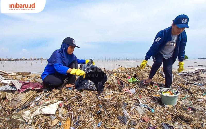 Mahasiswa tengah membersihkan sampah-sampah yang berserakan di kawasan bibir pantai Tambakrejo. (Inibaru.id/ Fitroh Nurikhsan)