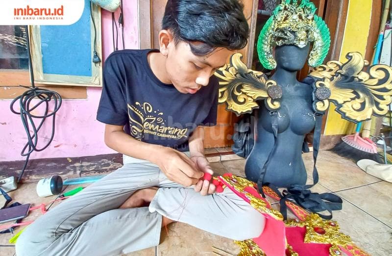 Adhe Sukma Pamungkas sedang menyelesaikan penggarapan pesanan kostum. (Inibaru.id/ Fitroh Nurikhsan)