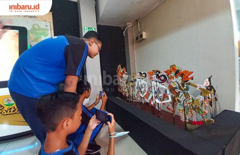 Beberapa anak sekolah terlihat sedang memotret wayang kulit yang dipamerkan di Museum Ranggawarsita. (Inibaru.id/ Fitroh Nurikhsan)